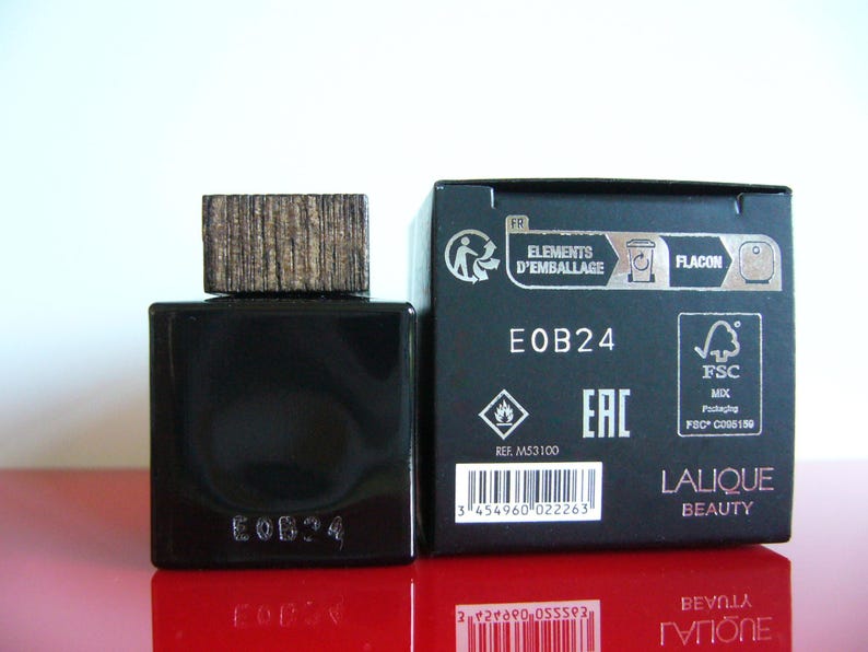 Peut inclure: Un flacon de parfum noir avec un bouchon en bois et une bo&icirc;te noire assortie. Le flacon et la bo&icirc;te portent l'inscription "EOB24". La bo&icirc;te porte &eacute;galement l'inscription "Lalique Beauty".