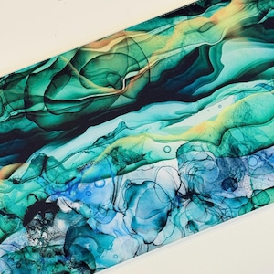 May include: Abstract art print featuring flowing layers of teal, turquoise, and emerald green hues. The design incorporates fluid shapes and patterns, with hints of yellow and blue, creating a dynamic and colorful composition. The artwork has a modern aesthetic.