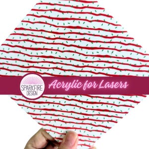 May include: A square sheet of white acrylic featuring a repeating pattern of horizontal wavy red lines interspersed with small green dashes. A circular logo with the text Sparkfire Design and the phrase Acrylic for Lasers is overlaid.