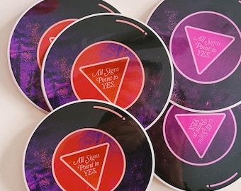 May include: Four black and white 8-ball stickers with a pink triangle and the text "All Signs Point to YES." The stickers are stacked on top of each other.