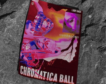 May include: A poster for Lady Gaga's Chromatica Ball tour. The poster features a pink and blue image of Lady Gaga in a futuristic outfit, with the text "Chromatica Ball" in a pink and white font.