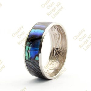 May include: A silver ring with a blue and green abalone shell inlay. The ring is set on a white background.