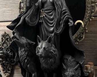 Könnte beinhalten: Schwarze Statue einer bekleideten Figur mit Krone, die eine Fackel und einen Halbmond hält, mit drei Wölfen am Sockel. Die Statue steht vor einem dekorativen ovalen Spiegel und einem Holzgrund.