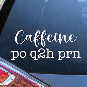 May include: White vinyl decal applied to a car window. The decal features the word "Caffeine" in a cursive font, with the phrase "po q2h prn" below it in a sans-serif font. The car's taillight is visible.