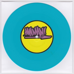 May include: A turquoise vinyl record with a yellow center circle. The center circle has a purple graphic of an arrow pointing to the right with the word "AWMAN!" written in purple.