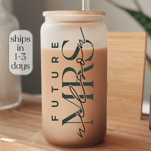 May include: A frosted glass tumbler with a bamboo lid and a straw. The tumbler has the text "FUTURE MRS" in dark green lettering and the text "never been" in black cursive lettering.