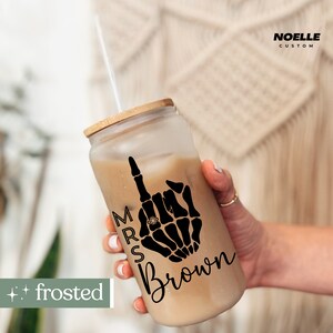 May include: A frosted glass tumbler with a black and white skeleton hand design and the text "Mrs. Brown".