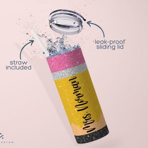 Op de afbeelding: Een gele, roze en zilveren glitterbeker met een zwart deksel en een rietje. De beker is gevormd als een potlood en heeft de tekst "Mrs. Johnson" erop. Het deksel is lekvrij en heeft een schuifopening.