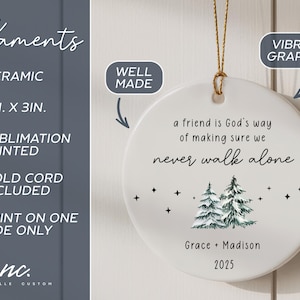 May include: A round white ceramic ornament measuring 3 inches by 3 inches, featuring a gold hanging cord. The text reads: a friend is God's way of making sure we never walk alone, Grace + Madison, 2025, with a graphic of two pine trees and stars.