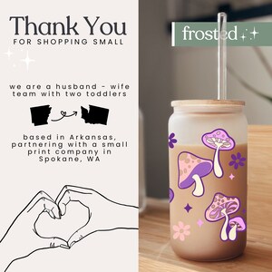 May include: A frosted glass tumbler with a bamboo lid and a reusable straw. The tumbler has a brown liquid inside and a pink and purple mushroom design with white flowers and stars. The text "frosted++" is on the right side of the image.