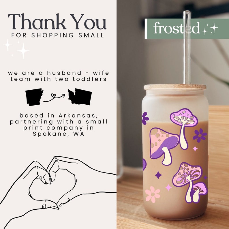 May include: A frosted glass tumbler with a bamboo lid and a reusable straw. The tumbler has a brown liquid inside and a pink and purple mushroom design with white flowers and stars. The text "frosted++" is on the right side of the image.