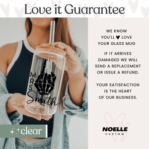 May include: A clear glass mug with a black skeleton hand design and the text "MRS Smith". The mug has a wooden lid and a straw. The text "Love it Guarantee" is at the top of the image. The text "WE KNOW YOU'LL LOVE YOUR GLASS MUG" is on the right side of the image. The text "IF IT ARRIVES DAMAGED WE WILL SEND A REPLACEMENT OR ISSUE A REFUND." is on the right side of the image. The text "YOUR SATISFACTION IS THE HEART OF OUR BUSINESS." is on the right side of the image. The text "NOELLE CUSTOM" is at the bottom right of the image.