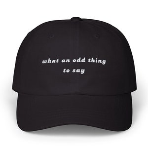 May include: Black baseball cap with white embroidered text that reads "what an odd thing to say".