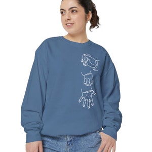 May include: A blue sweatshirt with a white outline of three hands on the front.