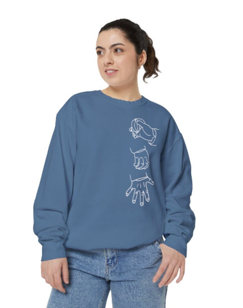 May include: A blue sweatshirt with a white outline of three hands on the front.