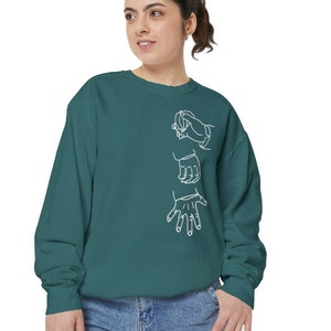 May include: A teal blue sweatshirt with a white outline of three hands in a sign language gesture.