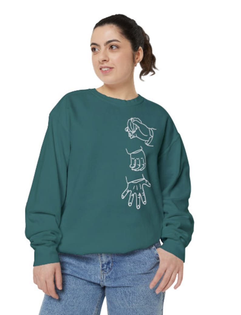 May include: A teal blue sweatshirt with a white outline of three hands in a sign language gesture.