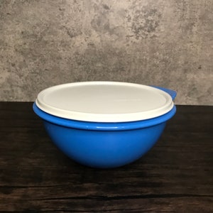 以下が含まれることがあります： 白い蓋が付いた青いプラスチック製のボウル。ボウルは丸く、表面が滑らかです。蓋には側面に小さな取っ手があります。