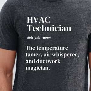 Pode incluir: Camiseta cinza escuro com o texto "HVAC Technician" em branco. A definição inclui "O domador de temperatura, o sussurrador de ar e o mágico de dutos". A camiseta é de gola redonda e manga curta.