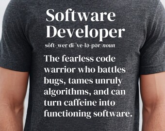 Op de afbeelding: Donkergrijs t-shirt met witte tekst "Software Developer" en een definitie. De tekst beschrijft een code-krijger die bugs bestrijdt en cafeïne omzet in functionele software.