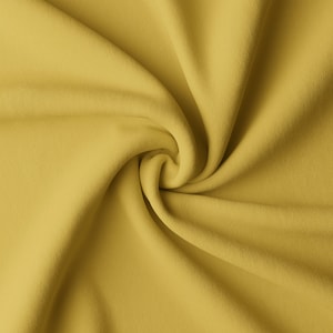 Può includere: Primo piano di un tessuto morbido di colore giallo con un motivo a spirale e texture.