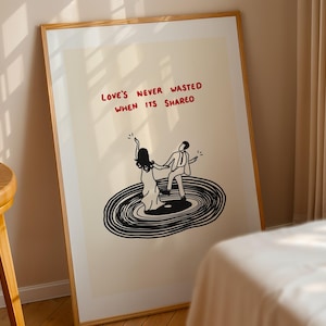 Pode incluir: Uma impress&atilde;o art&iacute;stica emoldurada com fundo creme e um desenho de linhas pretas de duas pessoas a dan&ccedil;ar num disco de vinil. O texto vermelho acima das figuras diz: "LOVE'S NEVER WASTED WHEN ITS SHARED." A moldura &eacute; de madeira clara.