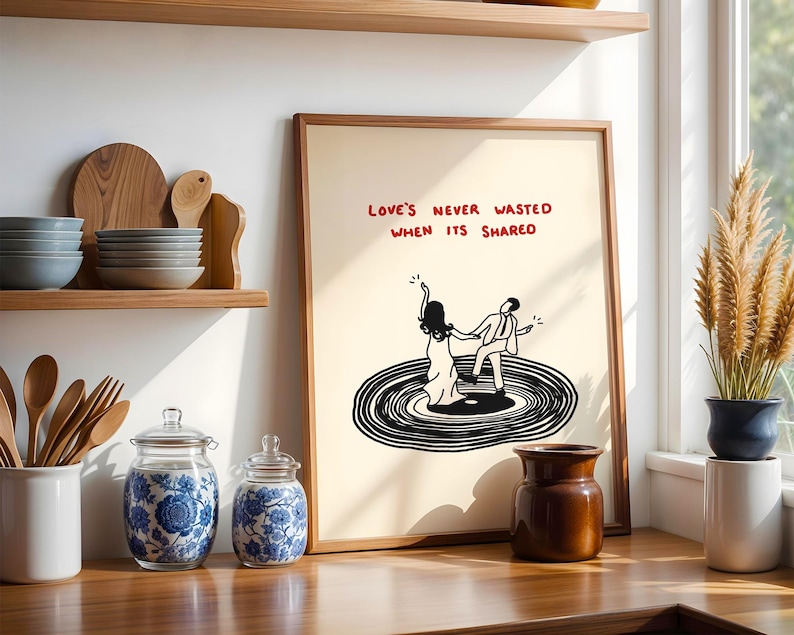 Pode incluir: Uma impress&atilde;o art&iacute;stica emoldurada com fundo creme, apresentando um desenho de linha preta de duas figuras dan&ccedil;ando em um disco de vinil. O texto acima das figuras diz "LOVE'S NEVER WASTED WHEN ITS SHARED" em letras vermelhas manuscritas.