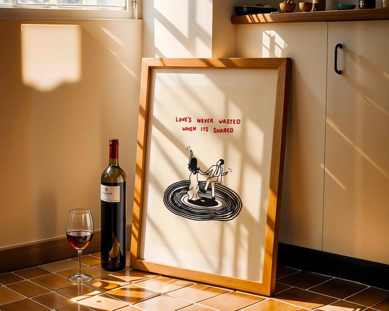 Pode incluir: Uma impress&atilde;o art&iacute;stica emoldurada com uma ilustra&ccedil;&atilde;o a preto e branco de duas figuras a dan&ccedil;ar num disco de vinil. O texto acima das figuras diz "LOVE'S NEVER WASTED WHEN ITS SHARED" em letras vermelhas. Moldura de madeira clara.