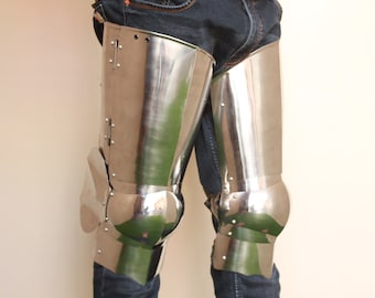 May include: Polished steel leg armor, featuring articulated knee and thigh plates. The armor is riveted together and reflects the surrounding environment. The design is reminiscent of medieval knight armor.