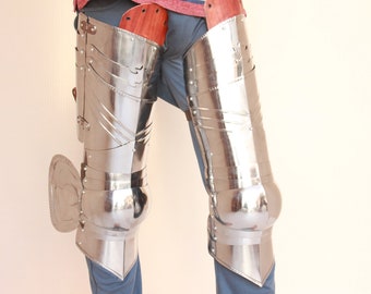 May include: Polished metal leg armor with articulated segments and decorative etching. The armor includes knee protection and a side shield. The metal reflects light, creating a bright, shiny appearance. The armor is designed to protect the legs.