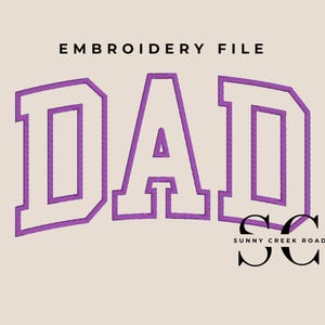 May include: An embroidery file design featuring the word DAD in large, purple-outlined block letters on a light beige background. Below the text, the letters SC appear in black with the text SUNNY CREEK ROAD underneath in a smaller font.
