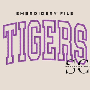 May include: An embroidery file design featuring the word "TIGERS" in a purple, block letter style. The text is arched and has a textured appearance. The words "EMBROIDERY FILE" are above the word "TIGERS". The Sunny Creek Road logo is below.