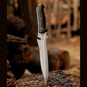 May include: A black-handled knife with a silver blade and a serrated edge. The knife has a small, curved hook on the top of the blade. The knife is resting on a piece of wood.