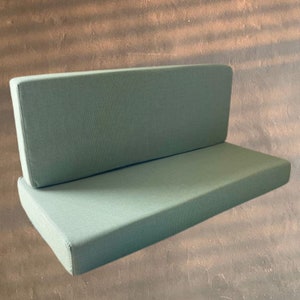 May include: A two-piece, light green, fabric sofa cushion set. The cushions are rectangular and have a smooth, even texture.