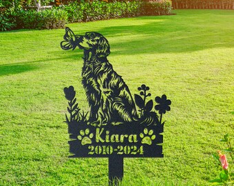 May include: Black metal garden stake memorial with a silhouette of a dog chasing a butterfly. The stake has a wooden sign with the name "Kiara" and the dates "2010-2024".