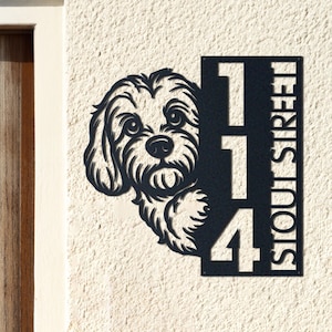 May include: Black metal house number sign featuring a dog silhouette and the numbers "114". The word "STOUT STREET" is vertically displayed on the right side of the sign. The sign is mounted on a textured, off-white wall.