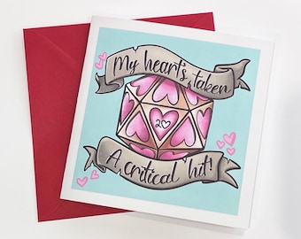 May include: A greeting card with a light blue background and a red envelope. The card features a pink and tan D20 die with heart-shaped faces and the text "My hearts taken" and "A critical hit!"