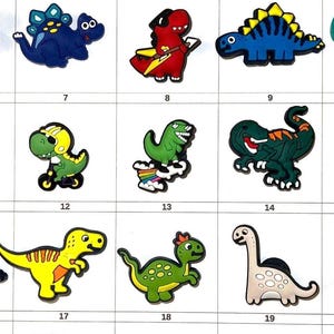 May include: A collection of colorful dinosaur-themed charms, each with a unique design. The charms are in various colors, including blue, green, yellow, and red. The image includes text that says "Item number is on the BOTTOM of each item" and "I only have ONE of each item."