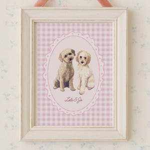 May include: A framed print featuring two small dogs in an oval frame with a pink gingham background. The white frame is topped with a pink velvet bow. The print is labeled "Lola & Jo".