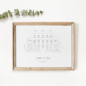 May include: A framed black and white line drawing of a stately home, with the names "Jonathan & Olivia" and "Dunstanburgh Castle 18.09.2023" written below. The frame is a light brown color.