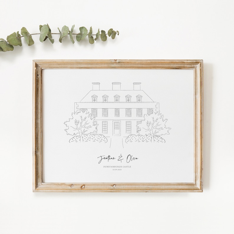 May include: A framed black and white line drawing of a stately home, with the names "Jonathan & Olivia" and "Dunstanburgh Castle 18.09.2023" written below. The frame is a light brown color.