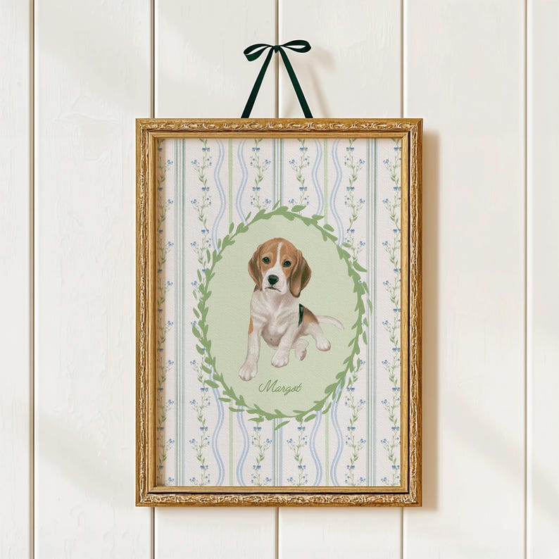 May include: A framed print featuring a beagle puppy illustration. The artwork is set within a gold-colored frame and is suspended by a dark green ribbon. The background has a floral pattern with blue and green accents. The puppy is surrounded by a green wreath and the name "Margot" is written below.