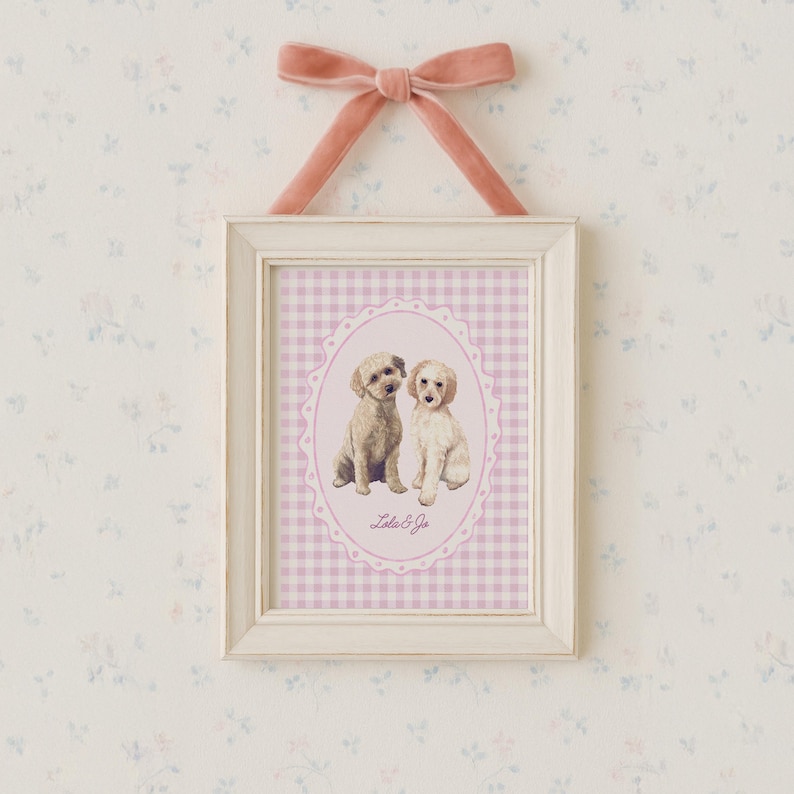 May include: A framed print featuring two small dogs in an oval frame with a pink gingham background. The white frame is topped with a pink velvet bow. The print is labeled "Lola & Jo".
