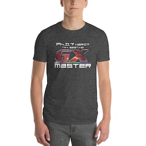May include: A dark heather grey t-shirt with a graphic of a video game logo. The logo is red, orange, yellow, green, blue, and purple. The text on the shirt reads "Ph.D.? Hard? Try beating GX on Master."