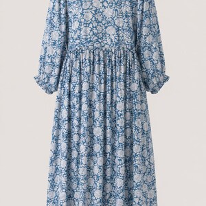 May include: A midi-length dress in a deep blue color featuring an all-over white floral pattern. The garment has long sleeves with gathered cuffs, a round neckline, and a gathered waistline that creates a full, flowing skirt silhouette.