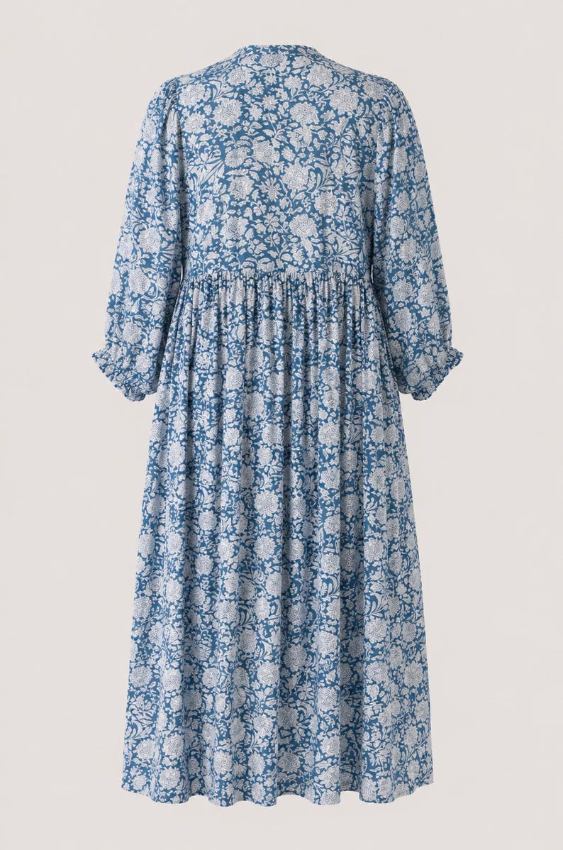 May include: A midi-length dress in a deep blue color featuring an all-over white floral pattern. The garment has long sleeves with gathered cuffs, a round neckline, and a gathered waistline that creates a full, flowing skirt silhouette.