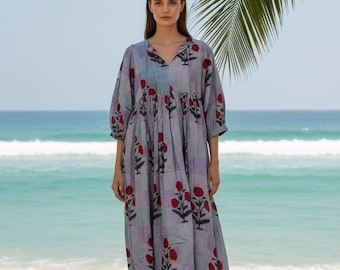 May include: A midi-length dress featuring a light purple and grey checkered pattern with a repeating red floral print. The garment has three-quarter length sleeves, a gathered waistline, and a V-neckline with thin tie closures at the front.
