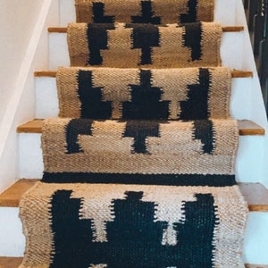 May include: A set of black and beige stair treads with a geometric pattern. The treads are made of a woven material and have a natural, rustic look.