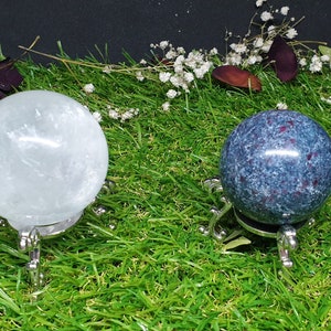May include: Two crystal spheres on metal stands. The sphere on the left is white and the sphere on the right is blue with red flecks.