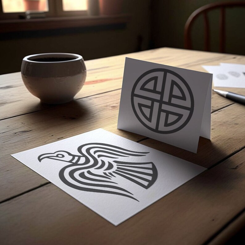 May include: Two white cards with black ink designs. One card features a stylized raven with its wings spread. The other card features a circular design with four interlocked knots.